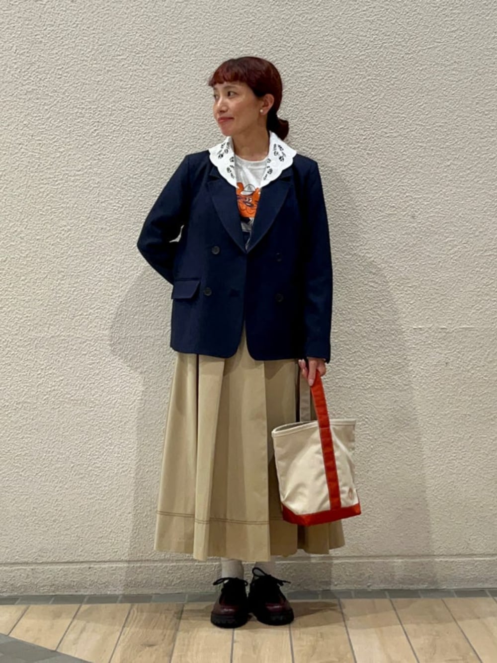 ブルー系のテーラードジャケット、ベージュ系のスカート、グレー系のTシャツ/カットソーを着用したレディースの秋コーディネートの1枚目の写真
