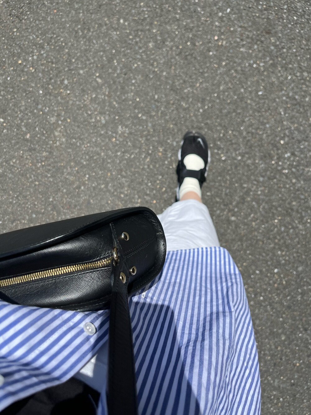 ブラック系のスニーカー、ブルー系のシャツ/ブラウス、ブラック系のショルダーバッグを着用したレディースの春コーディネートの1枚目の写真