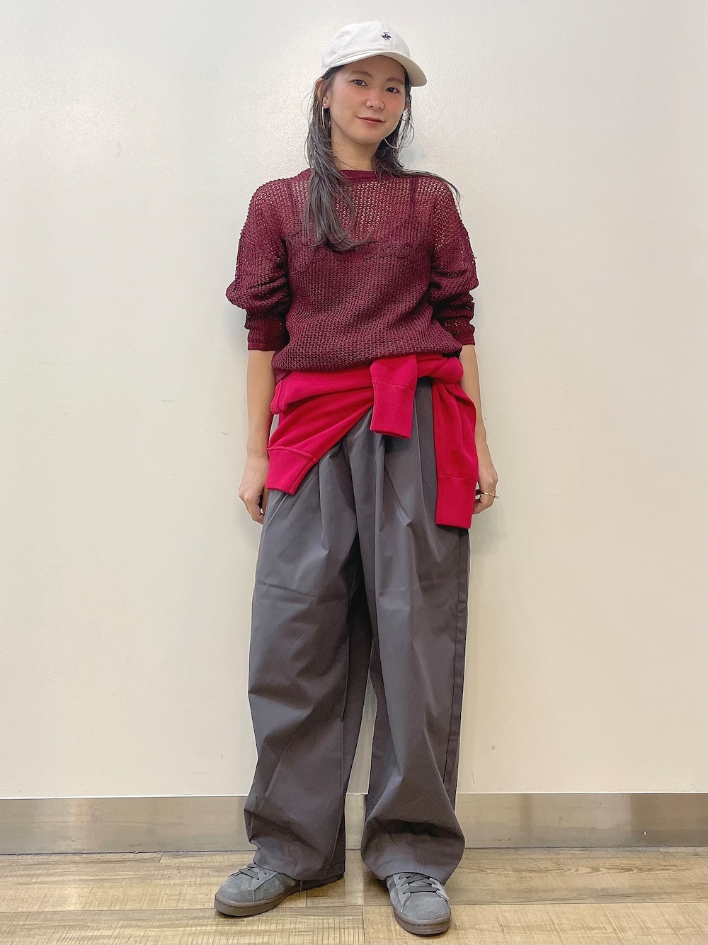 レッド系のニット/セーター、グレー系のその他パンツ、ベージュ系のキャップを着用したレディースの秋コーディネートの1枚目の写真