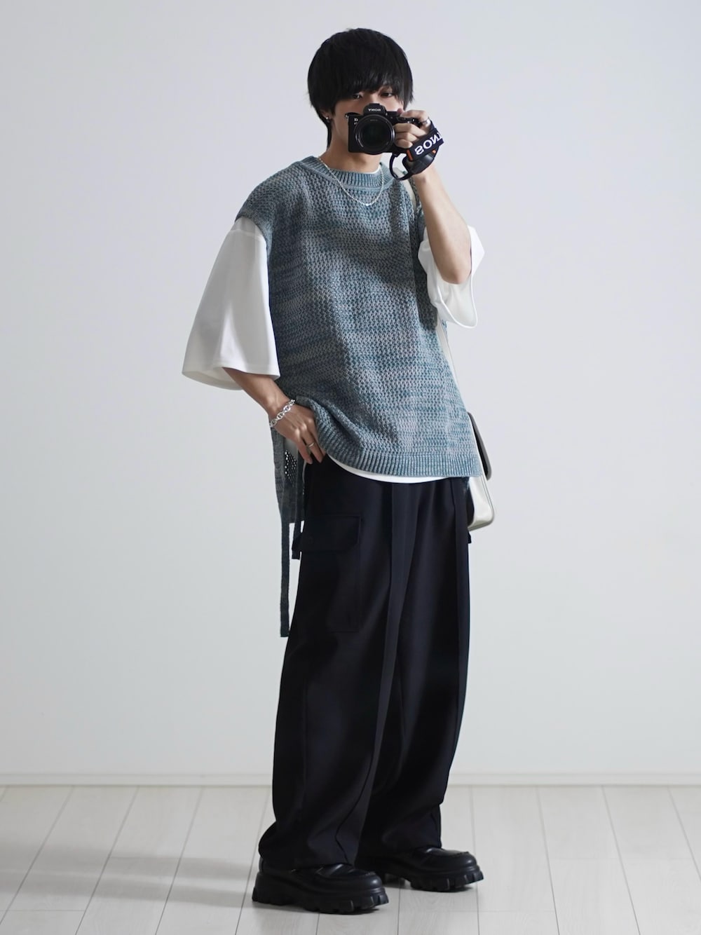 ブルー系のベスト、ホワイト系のTシャツ/カットソー、ブラック系のカーゴパンツを着用したメンズの春コーディネートの1枚目の写真