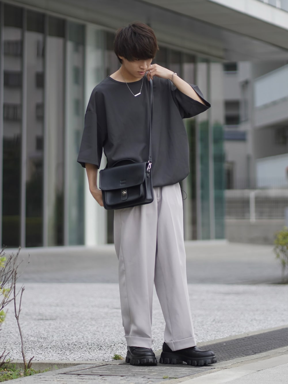 グレー系のTシャツ/カットソー、グレー系のスラックス、ブラック系のショルダーバッグを着用したメンズの夏コーディネートの1枚目の写真