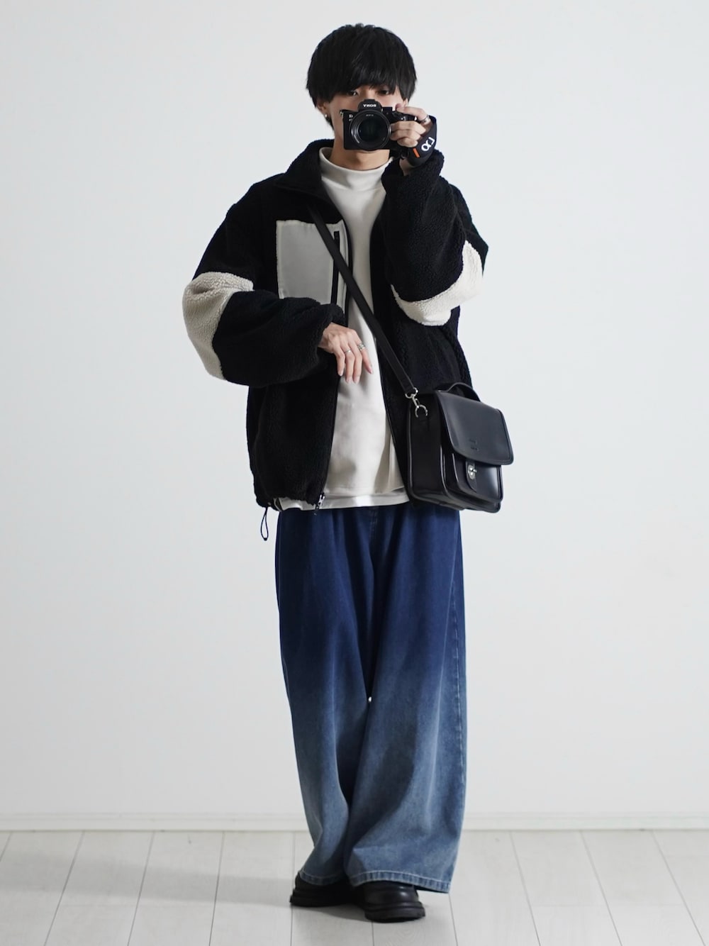 ブラック系のブルゾン、ホワイト系のTシャツ/カットソー、ブルー系のデニムパンツを着用したメンズの秋コーディネートの1枚目の写真