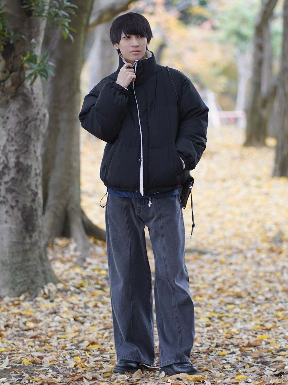 ブラック系のダウンジャケット/コート、ブルー系のニット/セーター、ブラック系のデニムパンツを着用したメンズの冬コーディネートの1枚目の写真