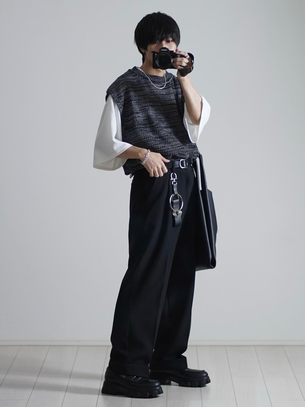 ブラック系のベスト、ホワイト系のTシャツ/カットソー、ブラック系のスラックスを着用したメンズの春コーディネートの1枚目の写真