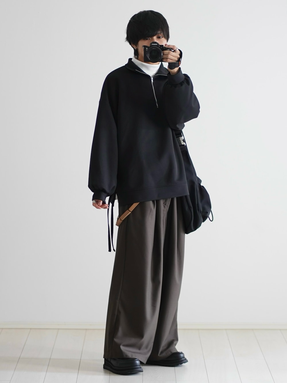 ブラック系のスウェット、ホワイト系のTシャツ/カットソー、ブラウン系のスラックスを着用したメンズの秋コーディネートの1枚目の写真