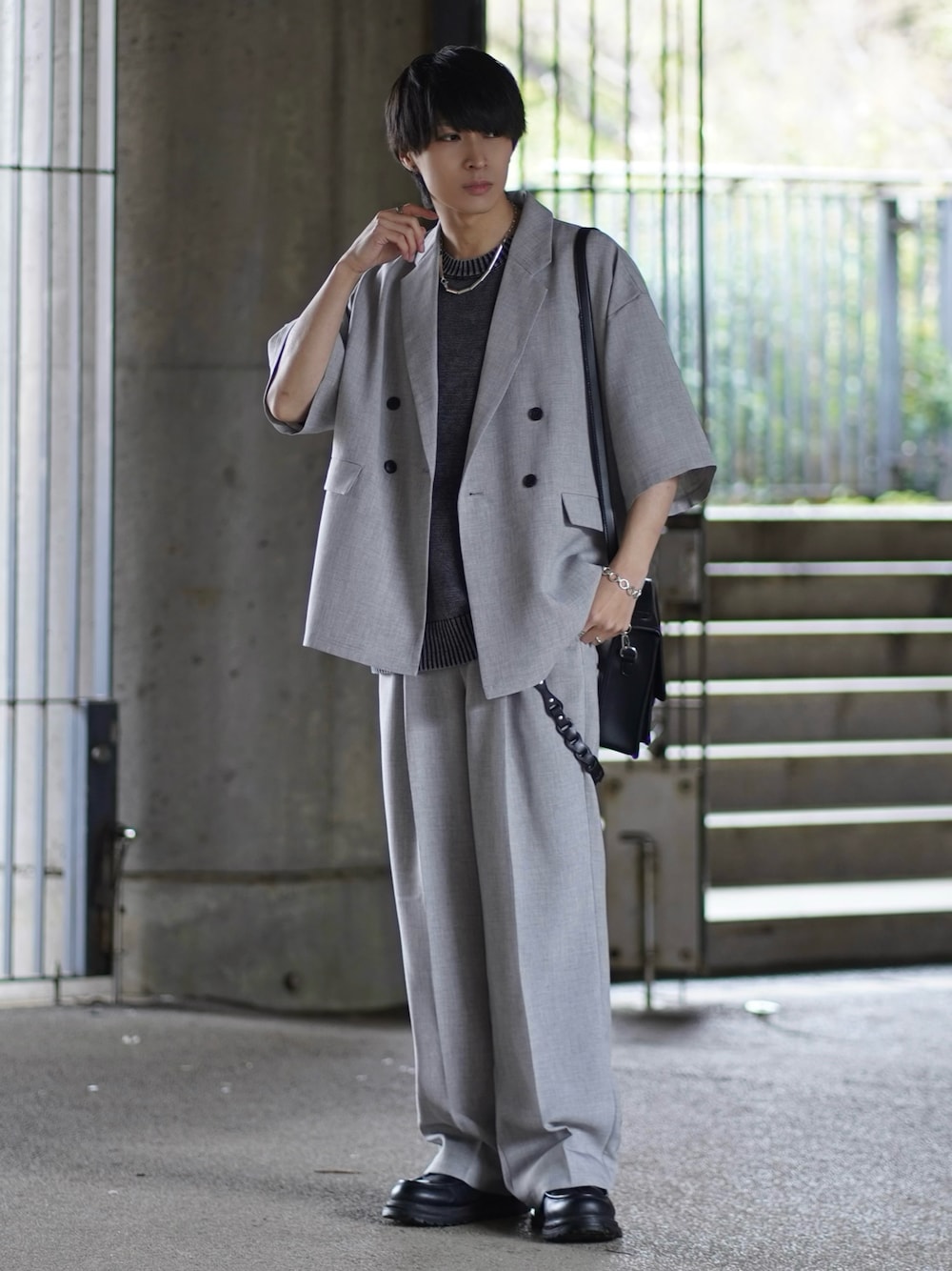 グレー系のセットアップ、ブラック系のニット/セーター、ブラック系のモカシン/デッキシューズを着用したメンズの春コーディネートの1枚目の写真