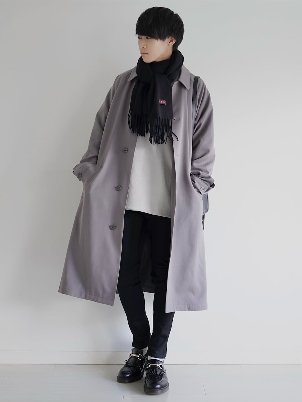 ベージュ系のステンカラーコート、ブラック系のデニムパンツ、ブラック系のドレスシューズを着用したメンズの冬コーディネートの1枚目の写真