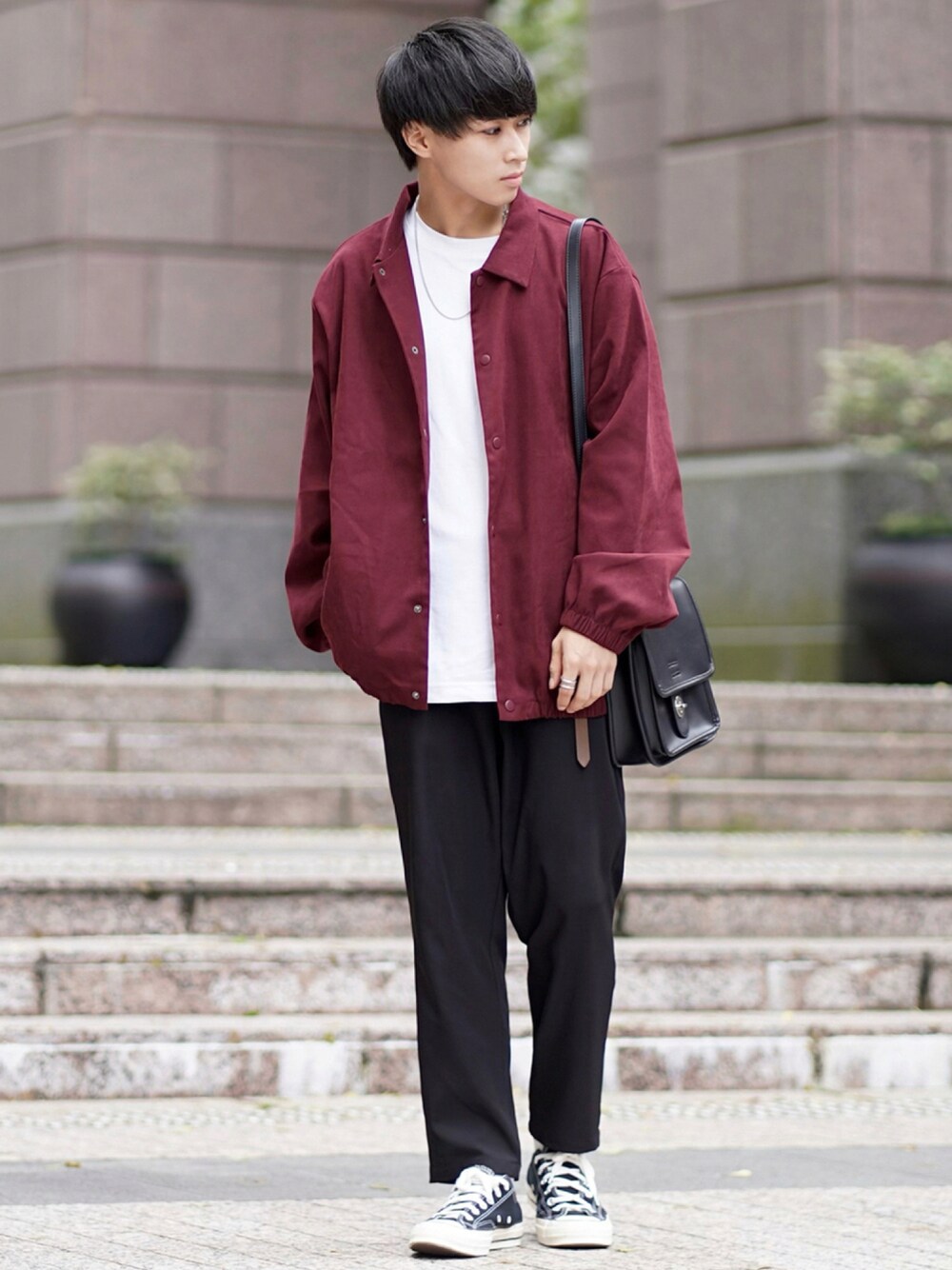 レッド系のブルゾン、ブラック系のセットアップ、ブラック系のショルダーバッグを着用したメンズの秋コーディネートの1枚目の写真