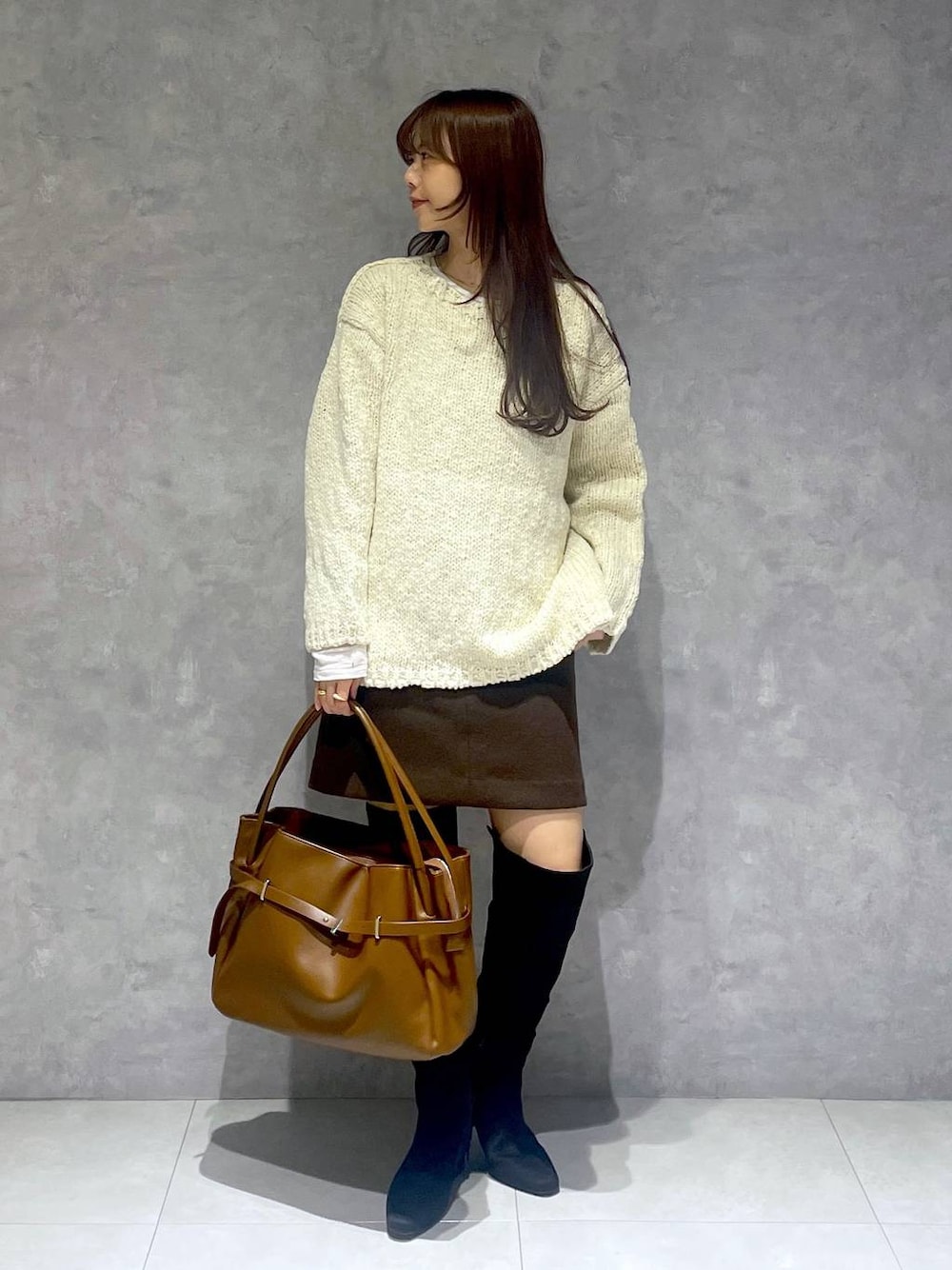 ブラウン系のスカート、ホワイト系のTシャツ/カットソー、ブラック系のブーツを着用したレディースの秋コーディネートの1枚目の写真