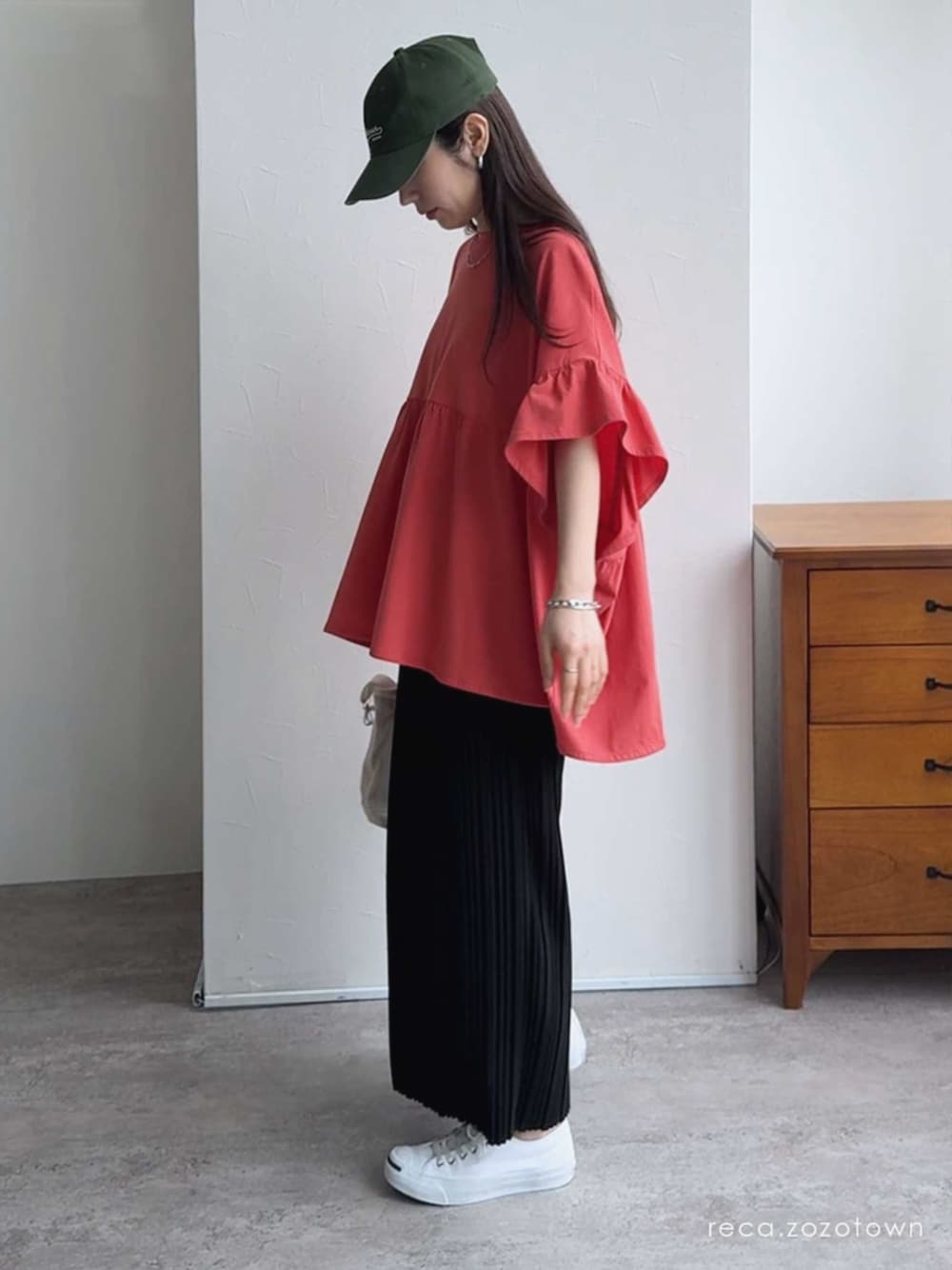 ブラック系のスカート、オレンジ系のTシャツ/カットソーを着用したレディースの春コーディネートの1枚目の写真