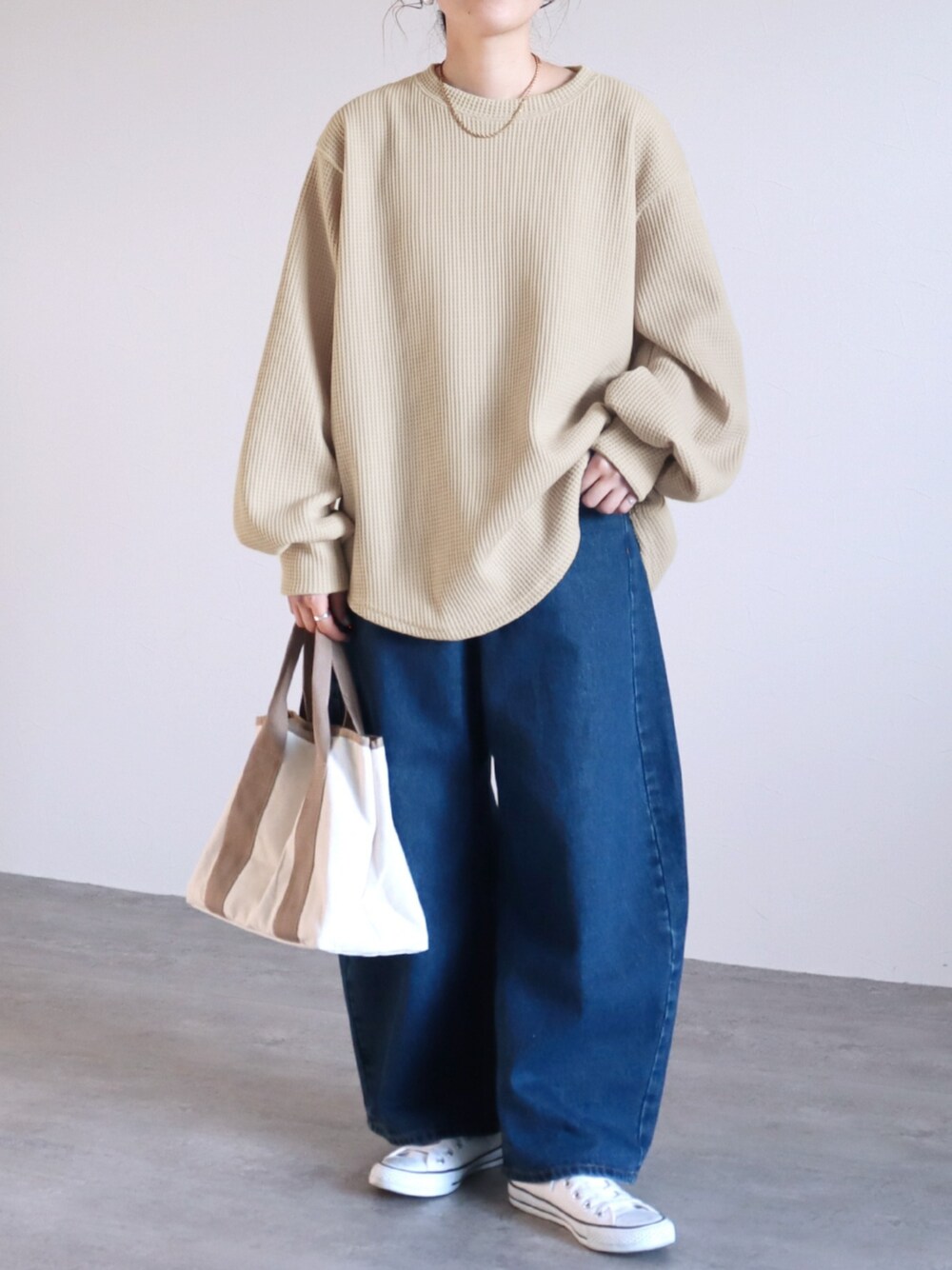 ブルー系のデニムパンツ、ベージュ系のスウェットを着用したレディースの冬コーディネートの1枚目の写真