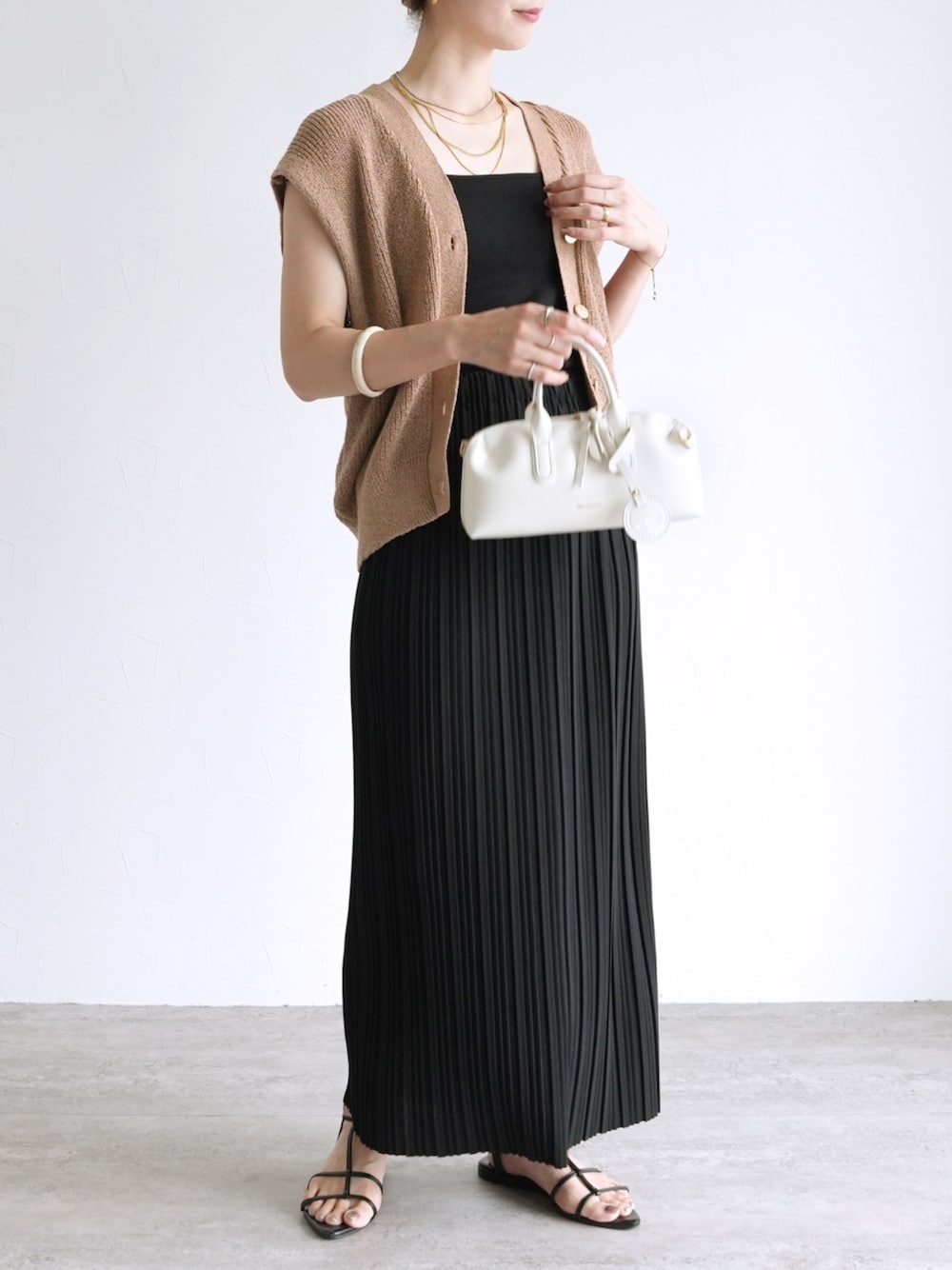 ブラック系のスカート、ベージュ系のベストを着用したレディースの夏コーディネートの1枚目の写真