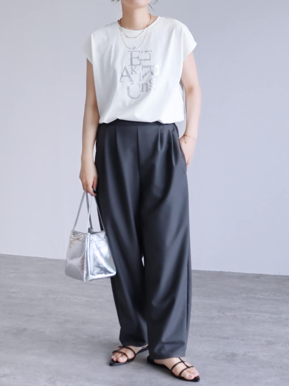 グレー系のスラックス、ホワイト系のTシャツ/カットソーを着用したレディースの春コーディネートの1枚目の写真