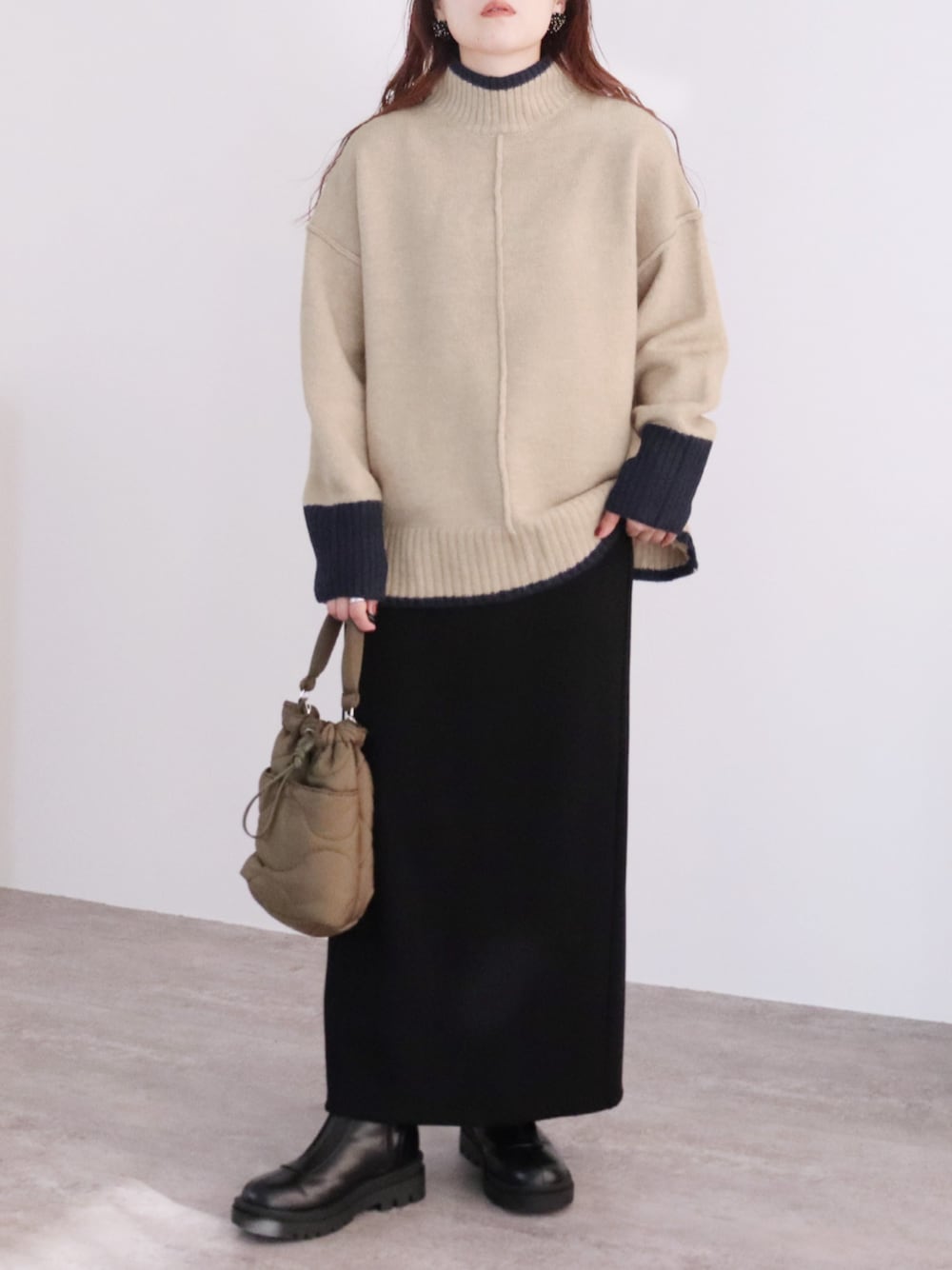 ベージュ系のニット/セーター、ブラック系のスカートを着用したレディースの秋コーディネートの1枚目の写真
