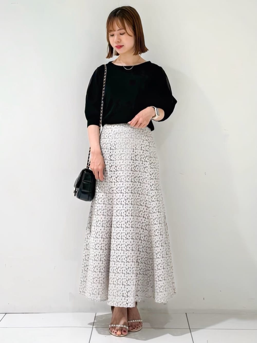 ブラック系のニット/セーター、ベージュ系のサンダル、ベージュ系のスカートを着用したレディースの夏コーディネートの1枚目の写真