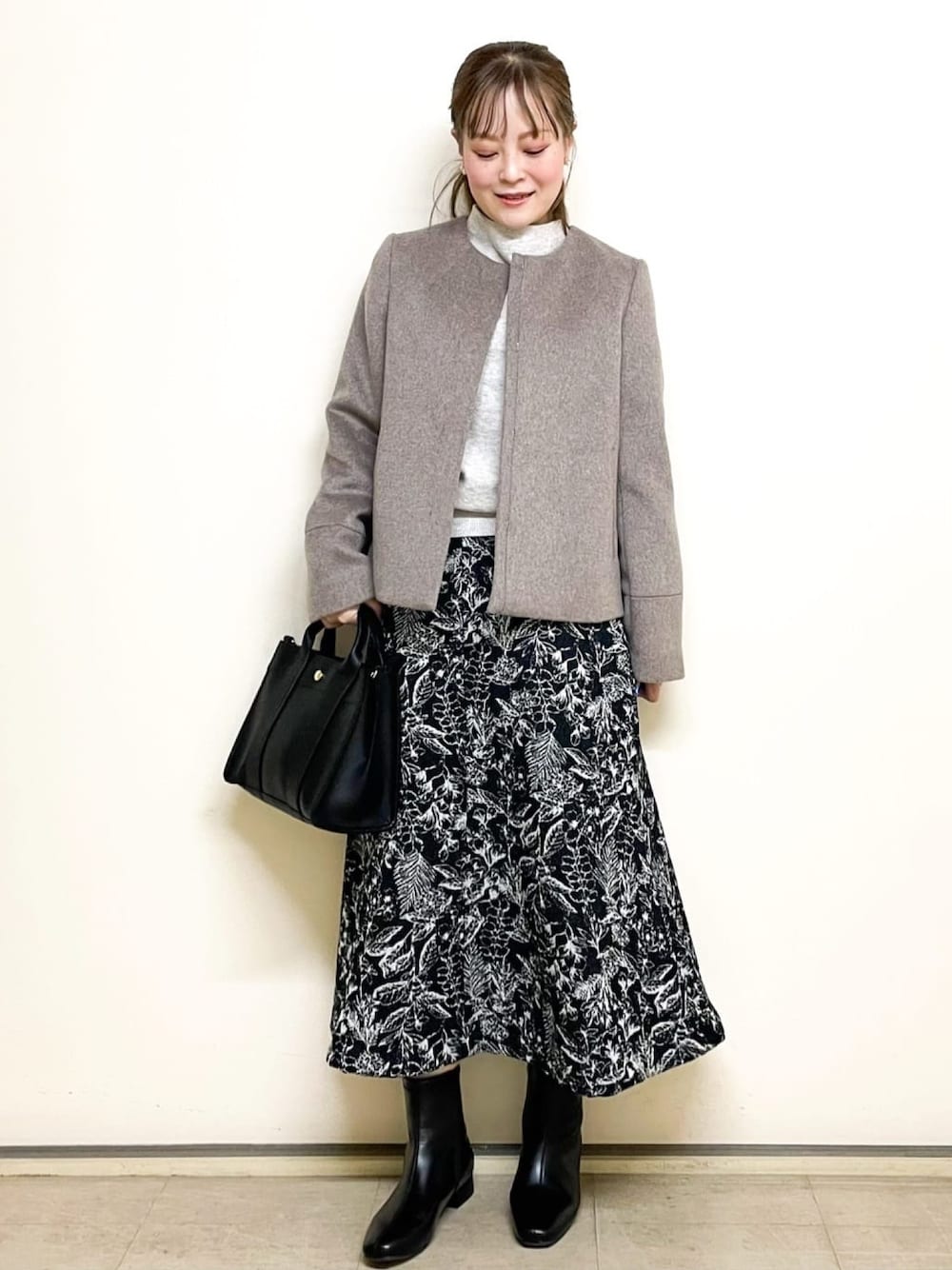 ベージュ系のニット/セーター、ブラック系のスカート、ブラック系のトートバッグを着用したレディースの冬コーディネートの1枚目の写真