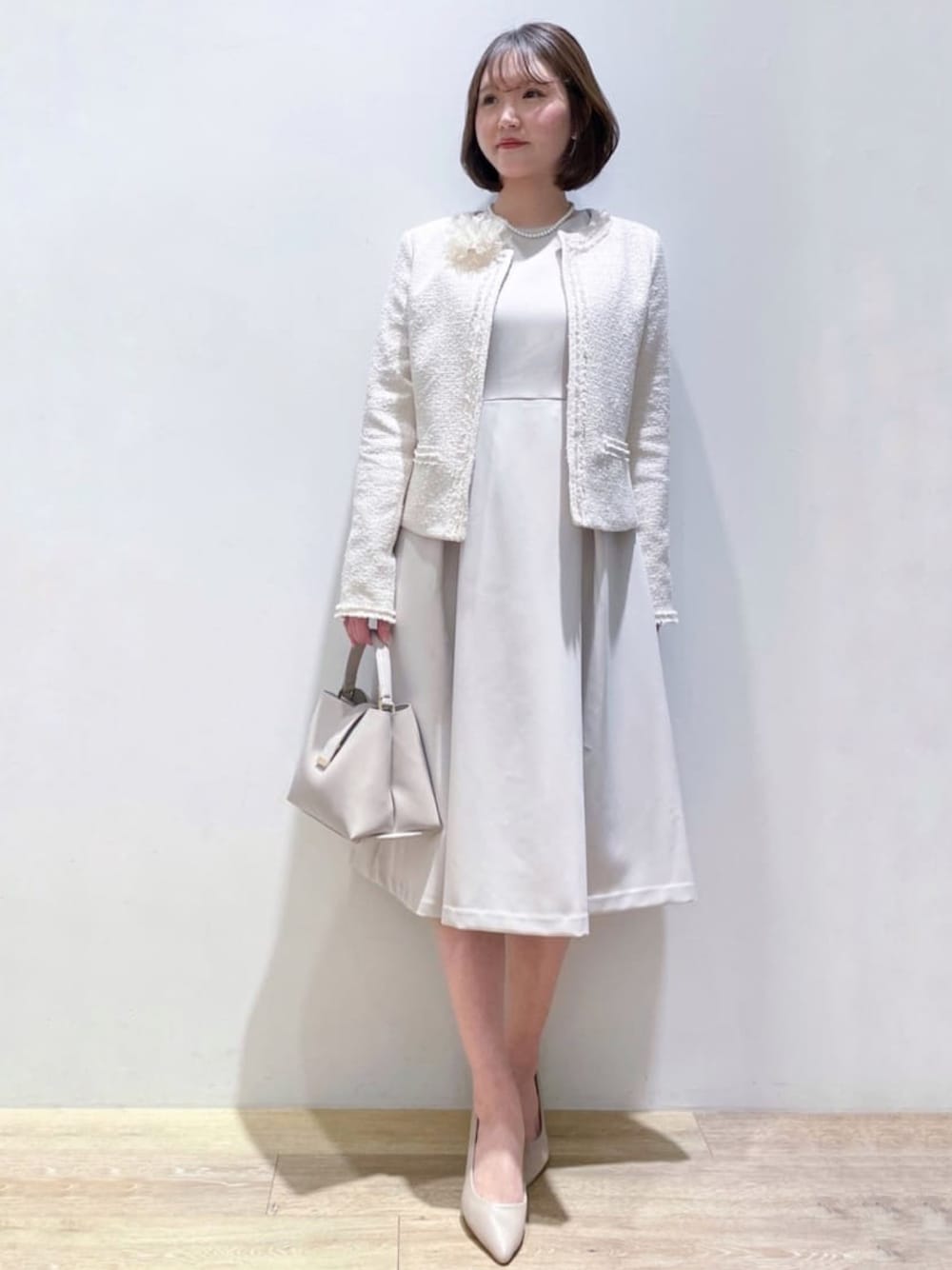 ベージュ系のワンピース、グレー系のショルダーバッグ、ベージュ系のパンプスを着用したレディースの冬コーディネートの1枚目の写真