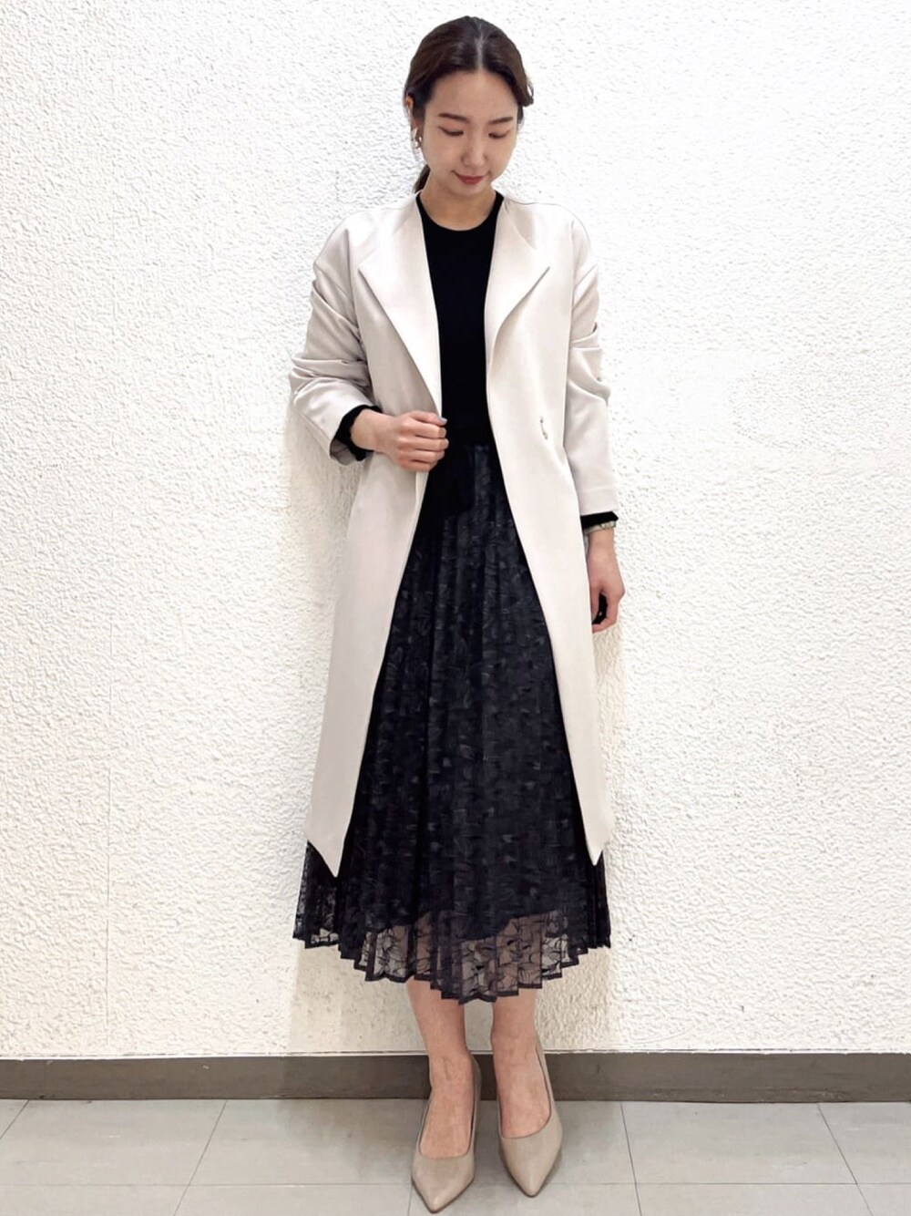 ブラック系のワンピース、ベージュ系のノーカラーコート、ベージュ系のパンプスを着用したレディースの春コーディネートの1枚目の写真