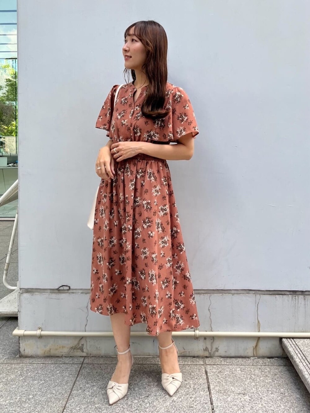 オレンジ系のワンピース、ホワイト系のショルダーバッグ、ホワイト系のパンプスを着用したレディースの夏コーディネートの1枚目の写真