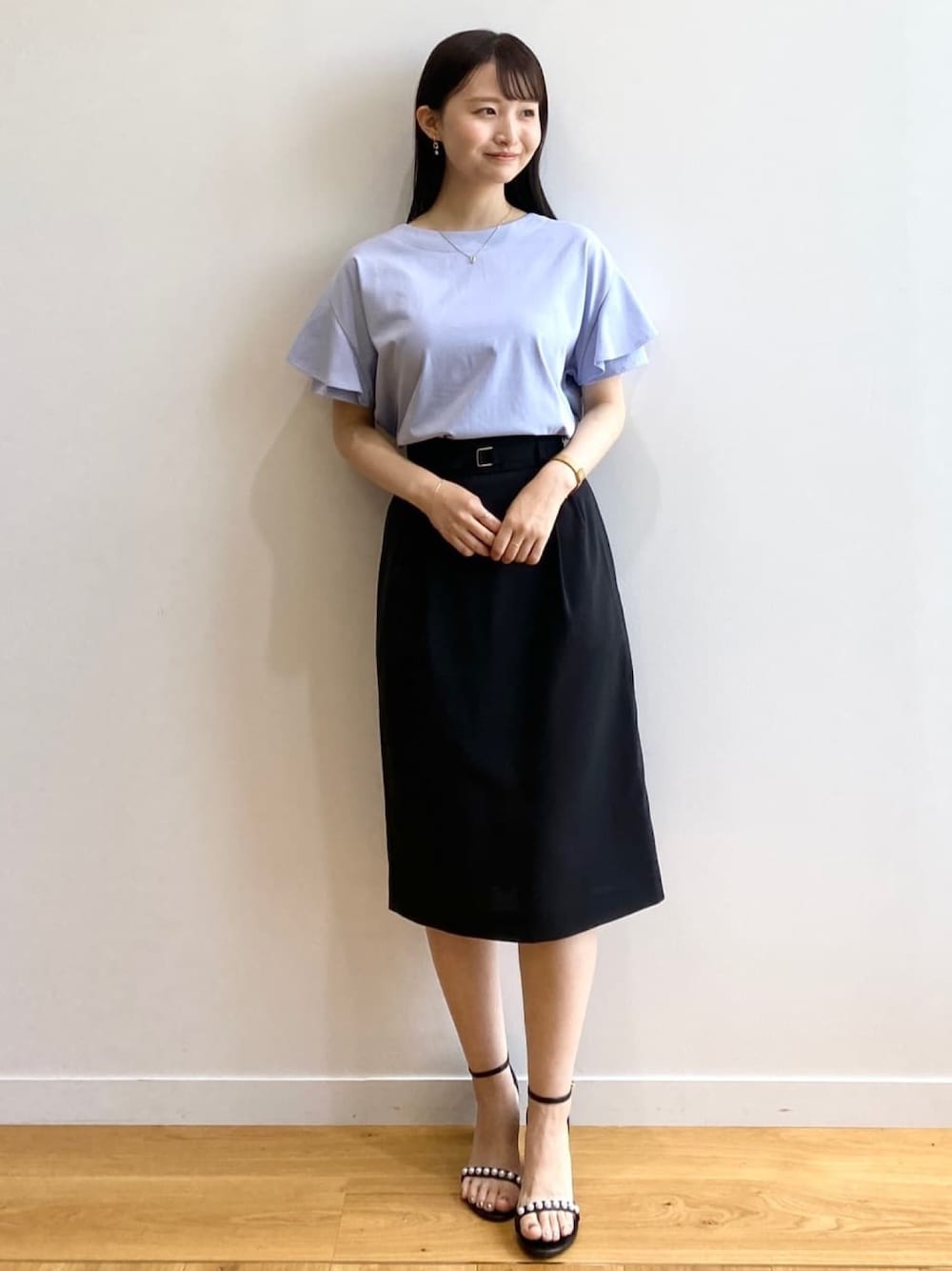ブラック系のスカート、ブルー系のTシャツ/カットソー、ブラック系のサンダルを着用したレディースの春コーディネートの1枚目の写真