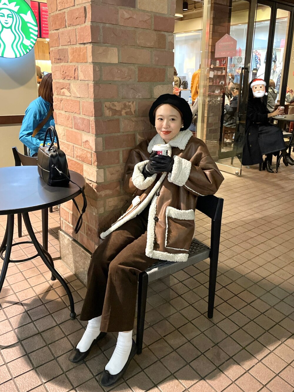 ブラウン系のムートンコート、ブラウン系のパンツ、ブラック系のバレエシューズを着用したレディースの秋コーディネートの1枚目の写真