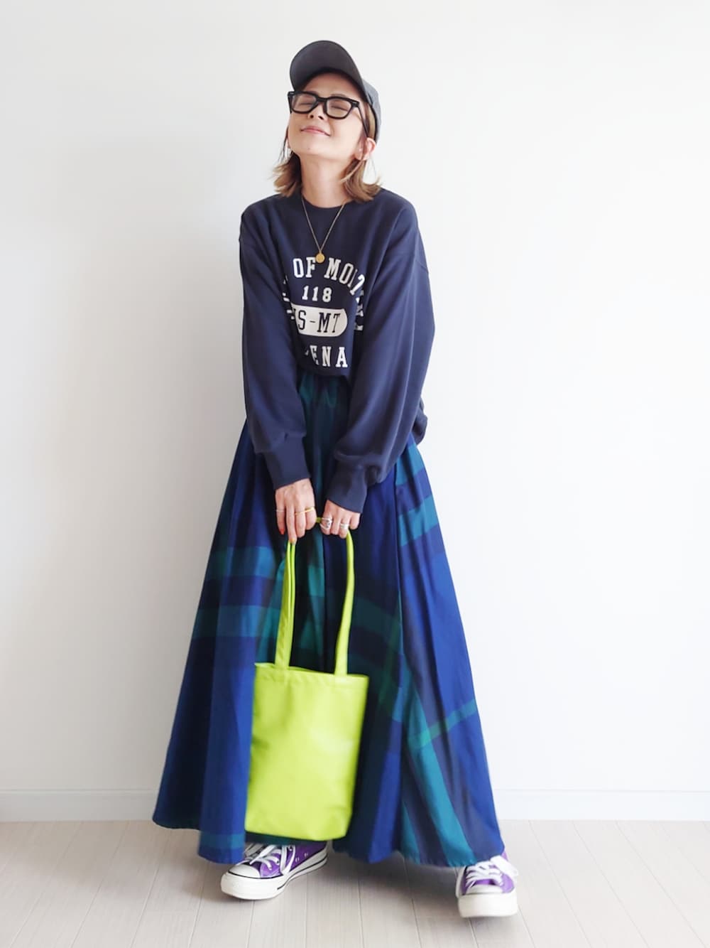 ブラック系のスウェット、ブルー系のスカート、パープル系のスニーカーを着用したレディースの秋コーディネートの1枚目の写真