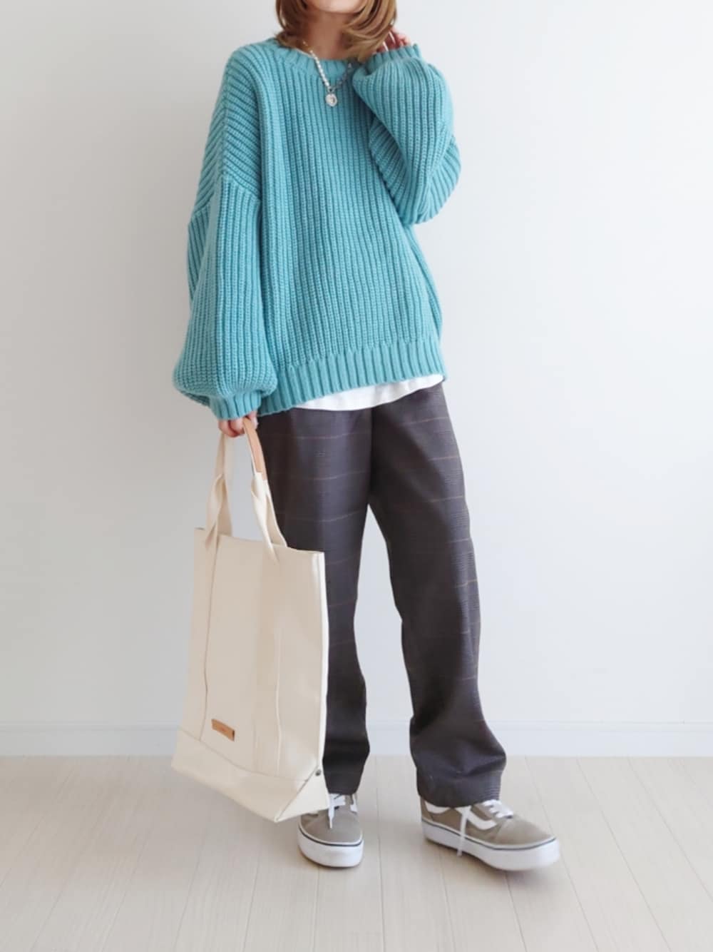 ブルー系のニット/セーター、ホワイト系のトートバッグ、ベージュ系のスニーカーを着用したレディースの秋コーディネートの1枚目の写真