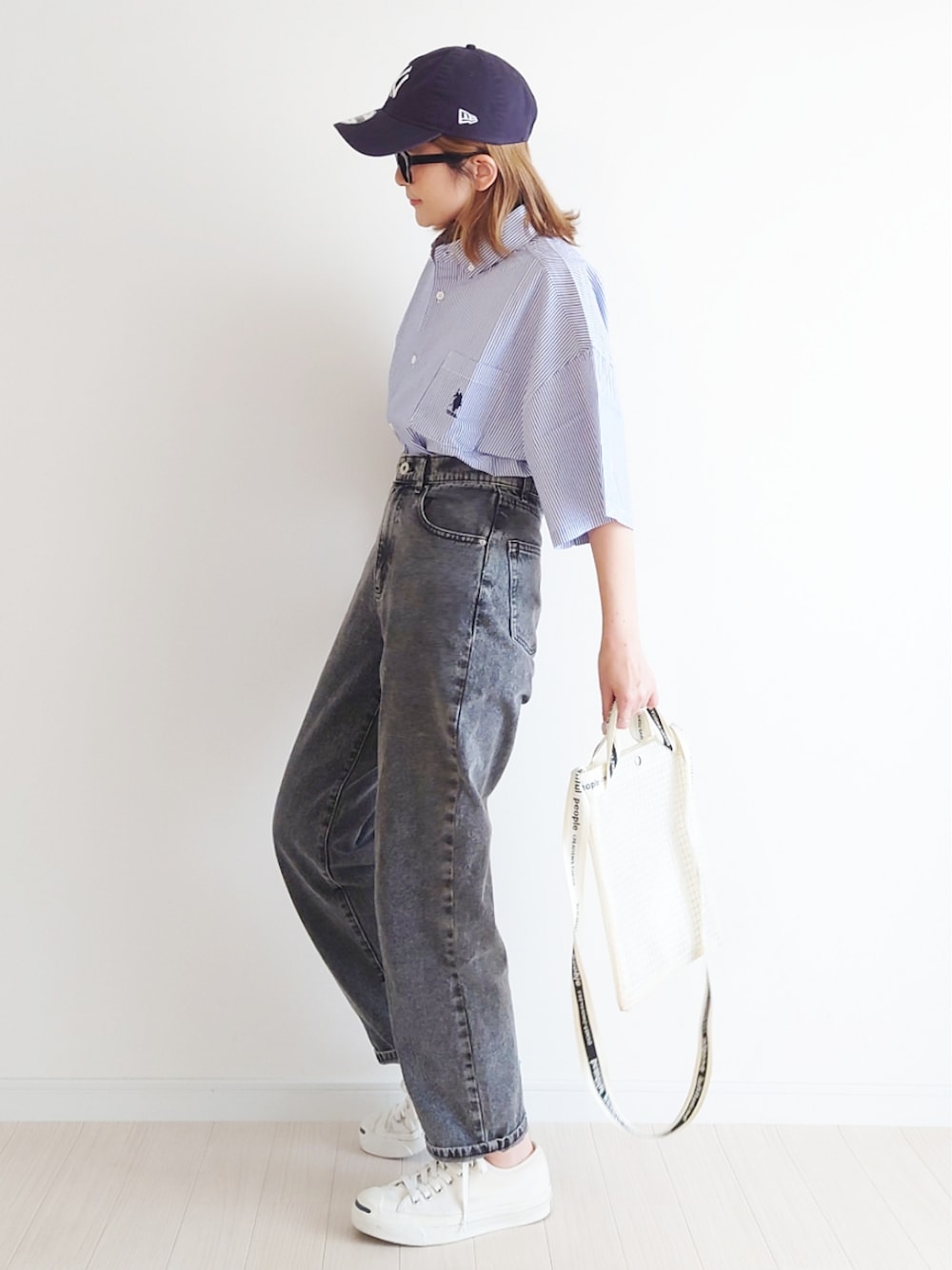 ブラック系のデニムパンツ、その他のショルダーバッグ、ホワイト系のスニーカーを着用したレディースの春コーディネートの1枚目の写真