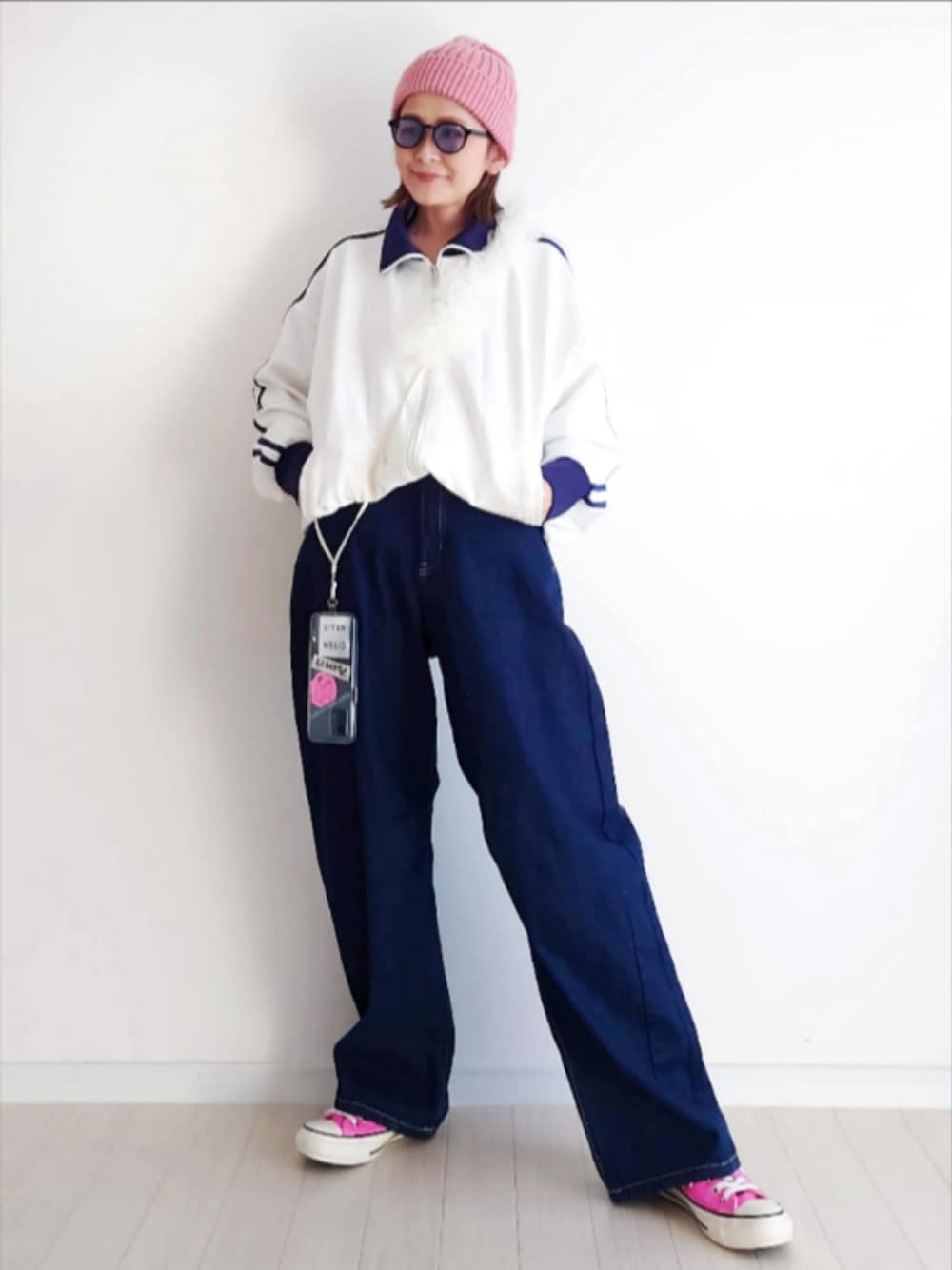 ホワイト系のジャージ、ブルー系のデニムパンツ、ピンク系のスニーカーを着用したレディースの冬コーディネートの1枚目の写真