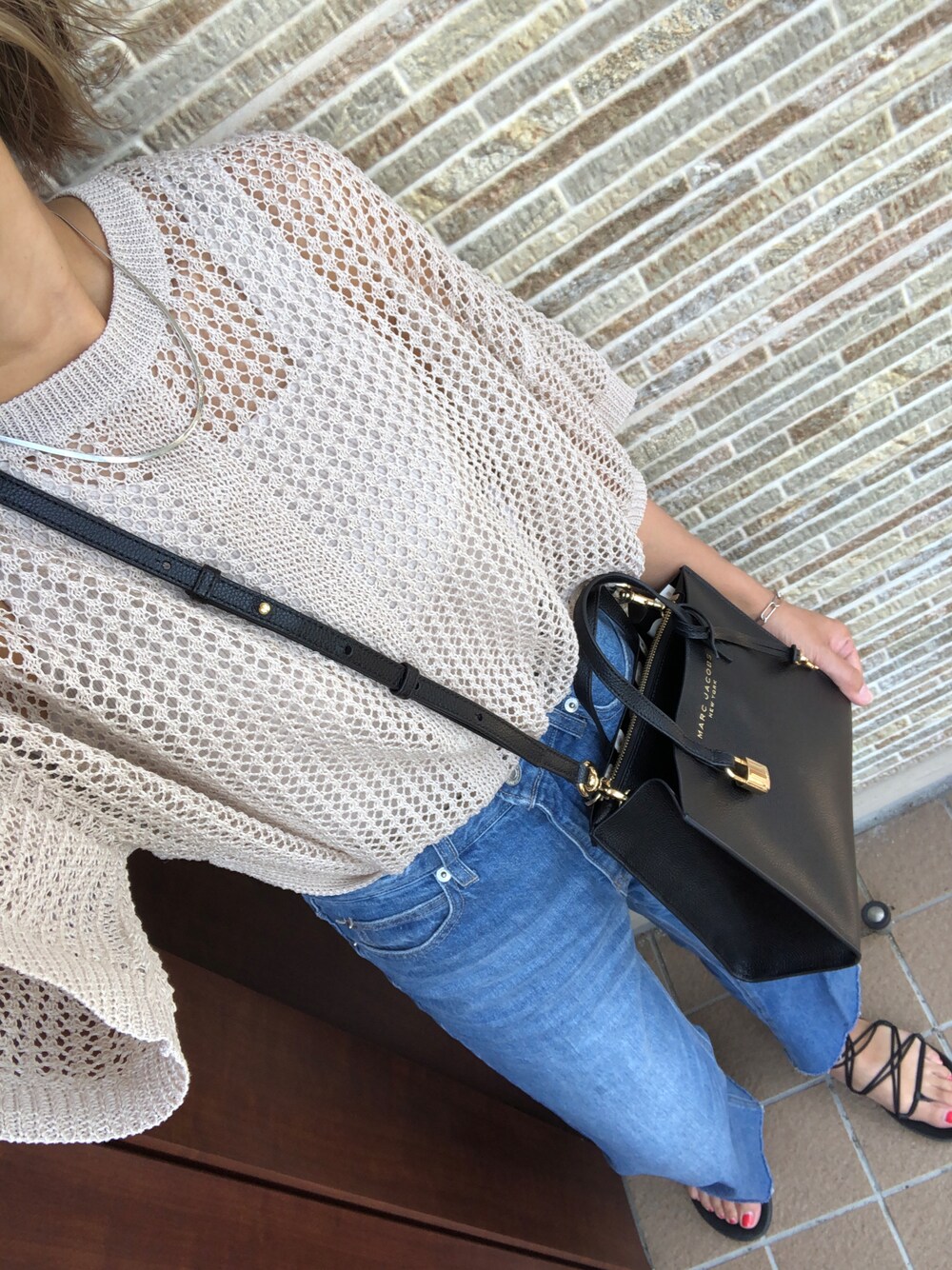 ブラック系のサンダル、ブルー系のデニムパンツ、ホワイト系のニット/セーターを着用したレディースの夏コーディネートの1枚目の写真