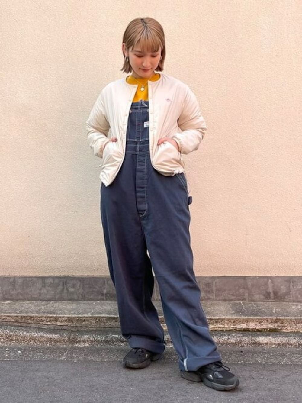 ホワイト系のノーカラージャケット、ブラック系のトートバッグ、ブルー系のサロペット/オーバーオールを着用したレディースの春コーディネートの1枚目の写真