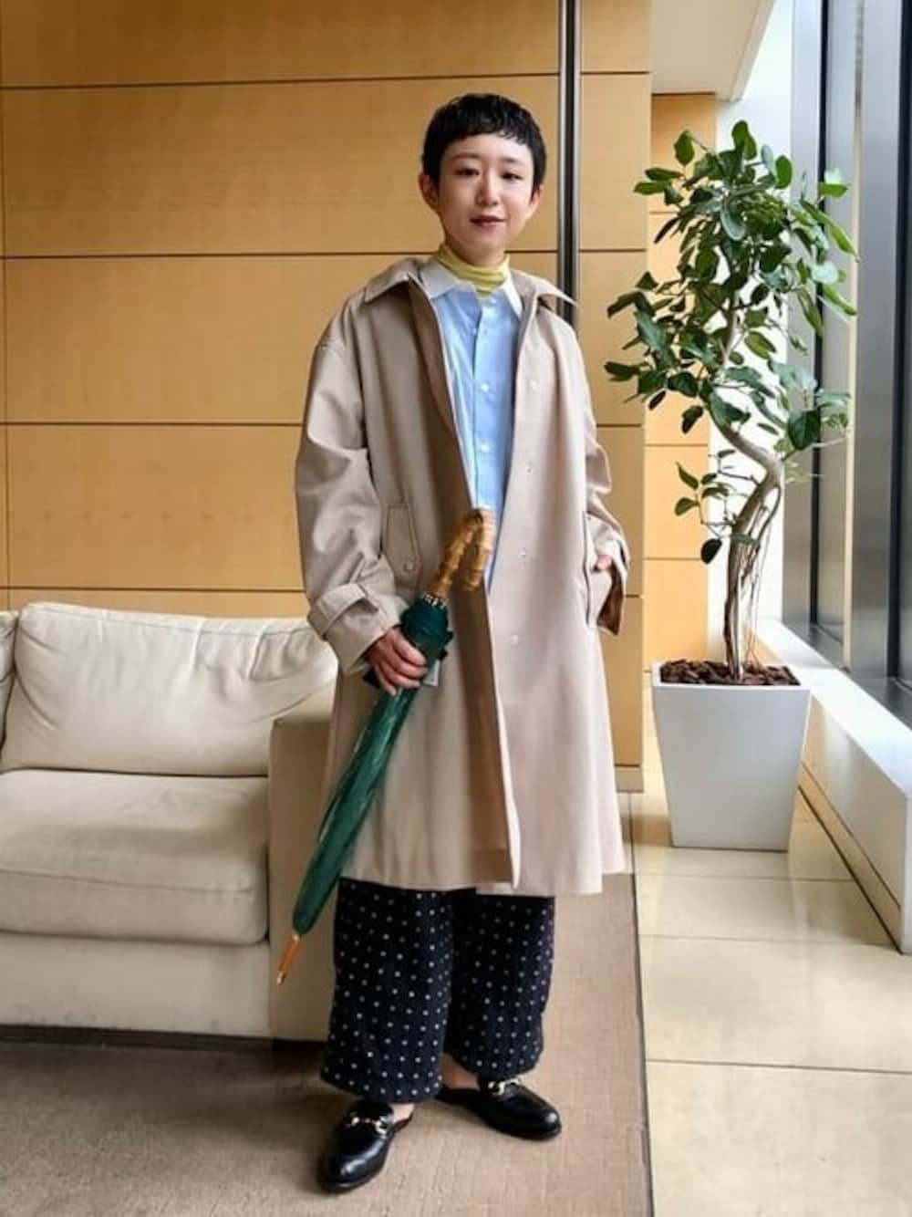 ベージュ系のステンカラーコート、ブルー系のシャツ/ブラウス、ブラック系のサンダルを着用したレディースの春コーディネートの1枚目の写真