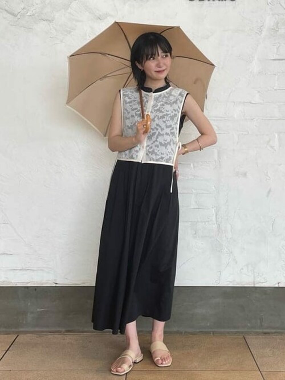 ブラック系のワンピース、ホワイト系のベスト、ベージュ系のサンダルを着用したレディースの夏コーディネートの1枚目の写真