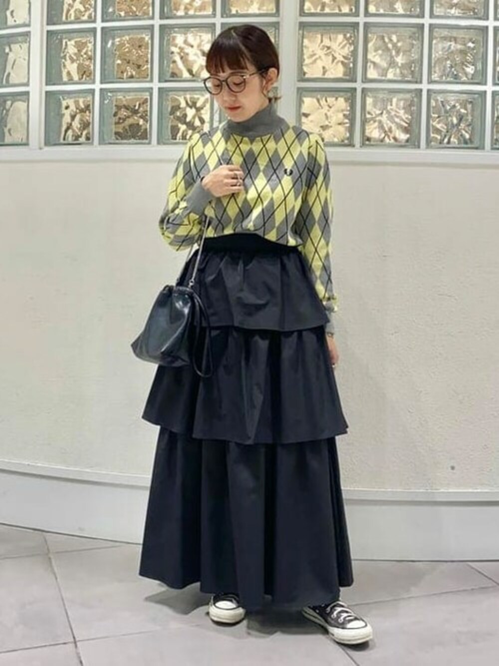 グレー系のニット/セーター、ブラック系のスカート、ブラック系のショルダーバッグを着用したレディースの夏コーディネートの1枚目の写真