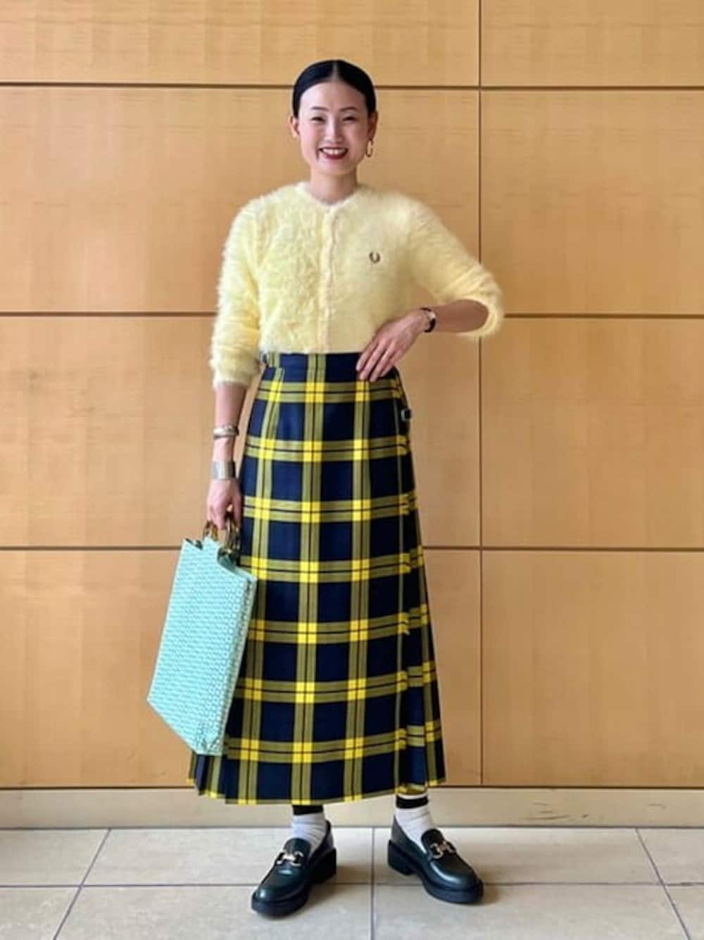 イエロー系のカーディガン/ボレロ、イエロー系のスカート、グリーン系のローファーを着用したレディースの秋コーディネートの1枚目の写真