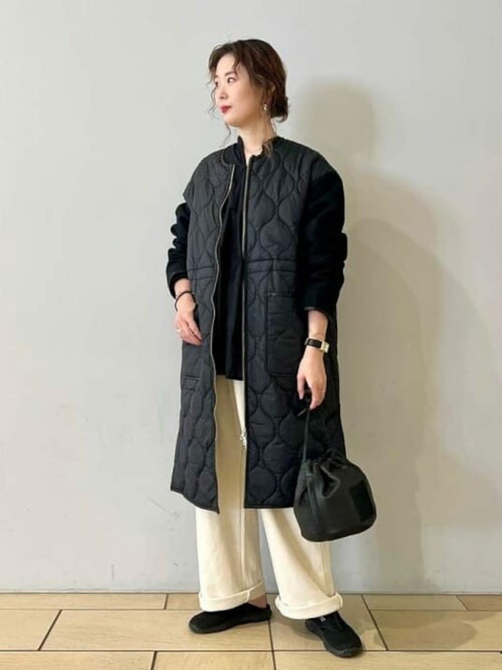 ブラック系のノーカラーコート、ベージュ系のスウェットパンツ、ブラック系のハンドバッグを着用したレディースの秋コーディネートの1枚目の写真