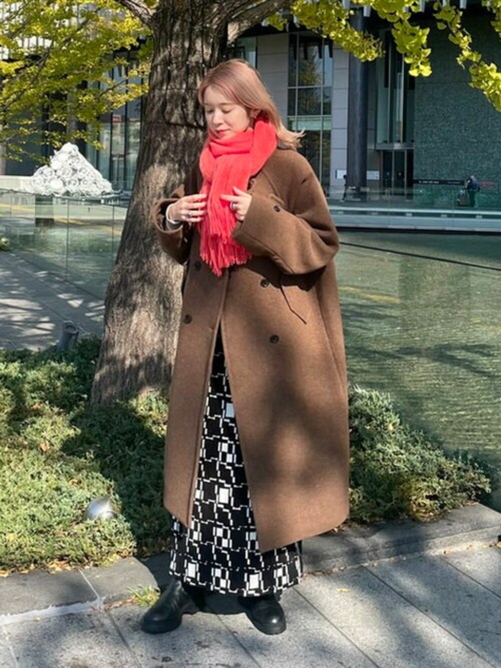 ブラウン系のその他アウター、ブラック系のスカート、ピンク系のマフラーを着用したレディースの秋コーディネートの1枚目の写真