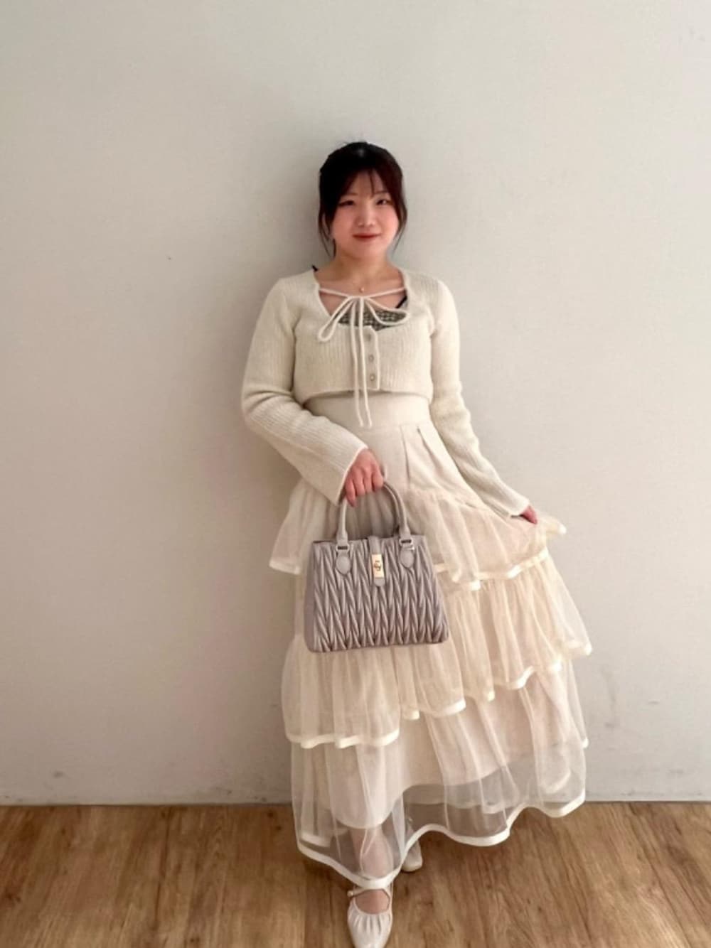 ホワイト系のパンプス、ベージュ系のショルダーバッグ、ホワイト系のスカートを着用したレディースの冬コーディネートの1枚目の写真