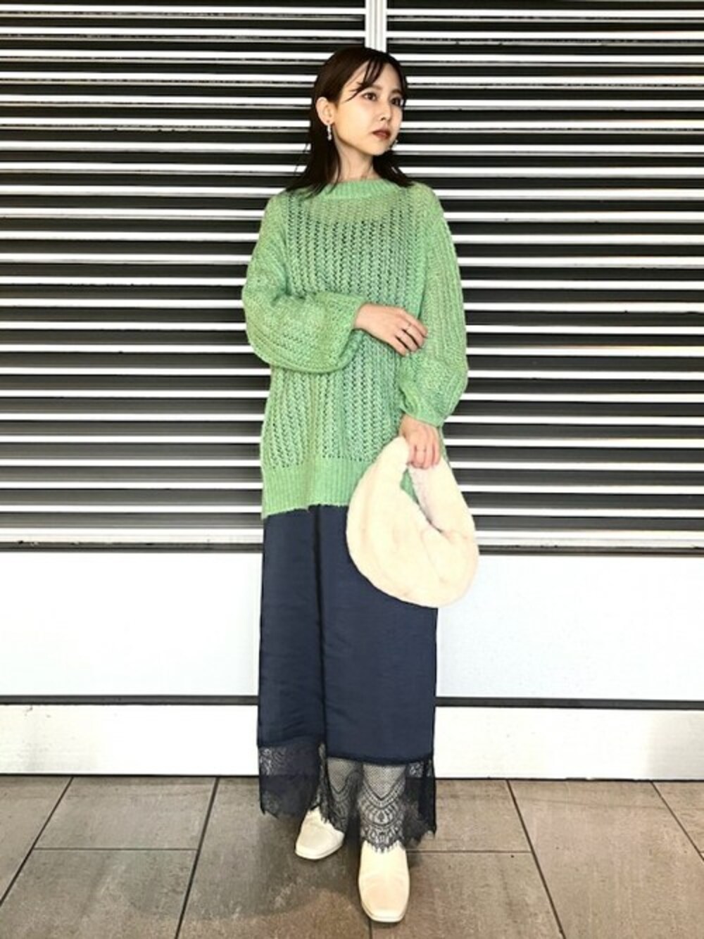 グリーン系のニット/セーター、ホワイト系のブーツ、その他のイヤリングを着用したレディースの秋コーディネートの1枚目の写真