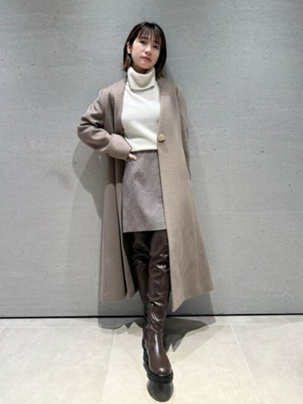 ブラウン系のチェスターコート、ホワイト系のニット/セーター、ブラウン系のスカートを着用したレディースの秋コーディネートの1枚目の写真