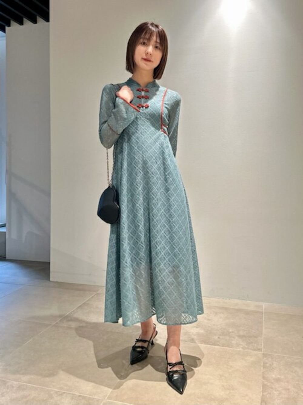 グリーン系のワンピース、ブルー系のデニムパンツ、ブラック系のショルダーバッグを着用したレディースの春コーディネートの1枚目の写真