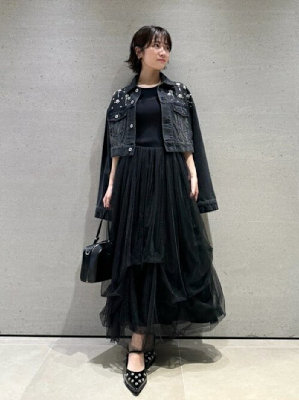 ブラック系のデニムジャケット、ブラック系のワンピース、ブラック系のハンドバッグを着用したレディースの夏コーディネートの1枚目の写真