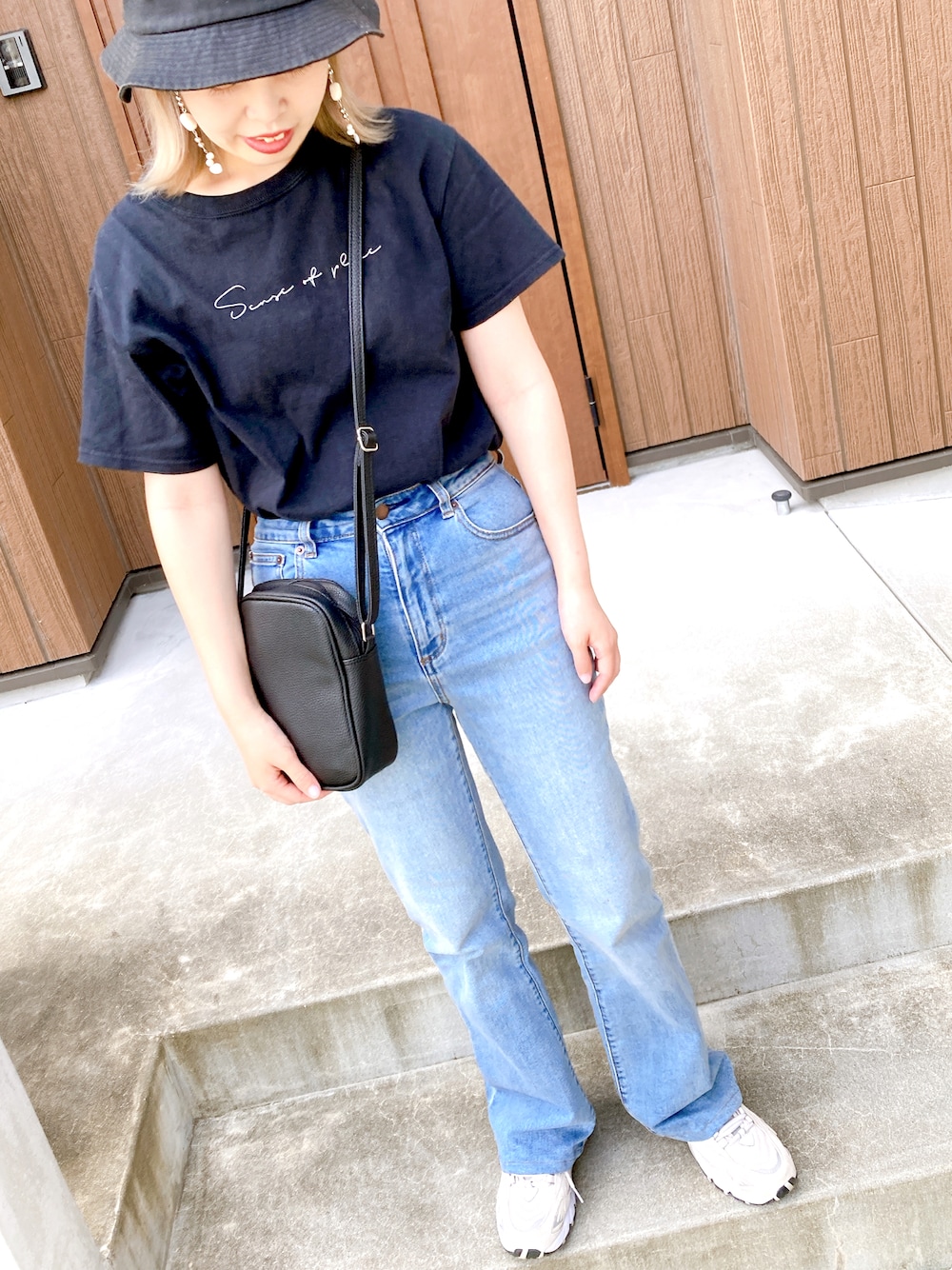 ブルー系のデニムパンツ、ベージュ系のスニーカー、ブラック系のTシャツ/カットソーを着用したレディースの夏コーディネートの1枚目の写真