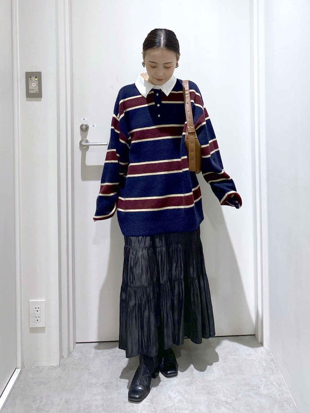 ブラック系のスカート、ブルー系のトップス、ブラウン系のハンドバッグを着用したレディースの冬コーディネートの1枚目の写真