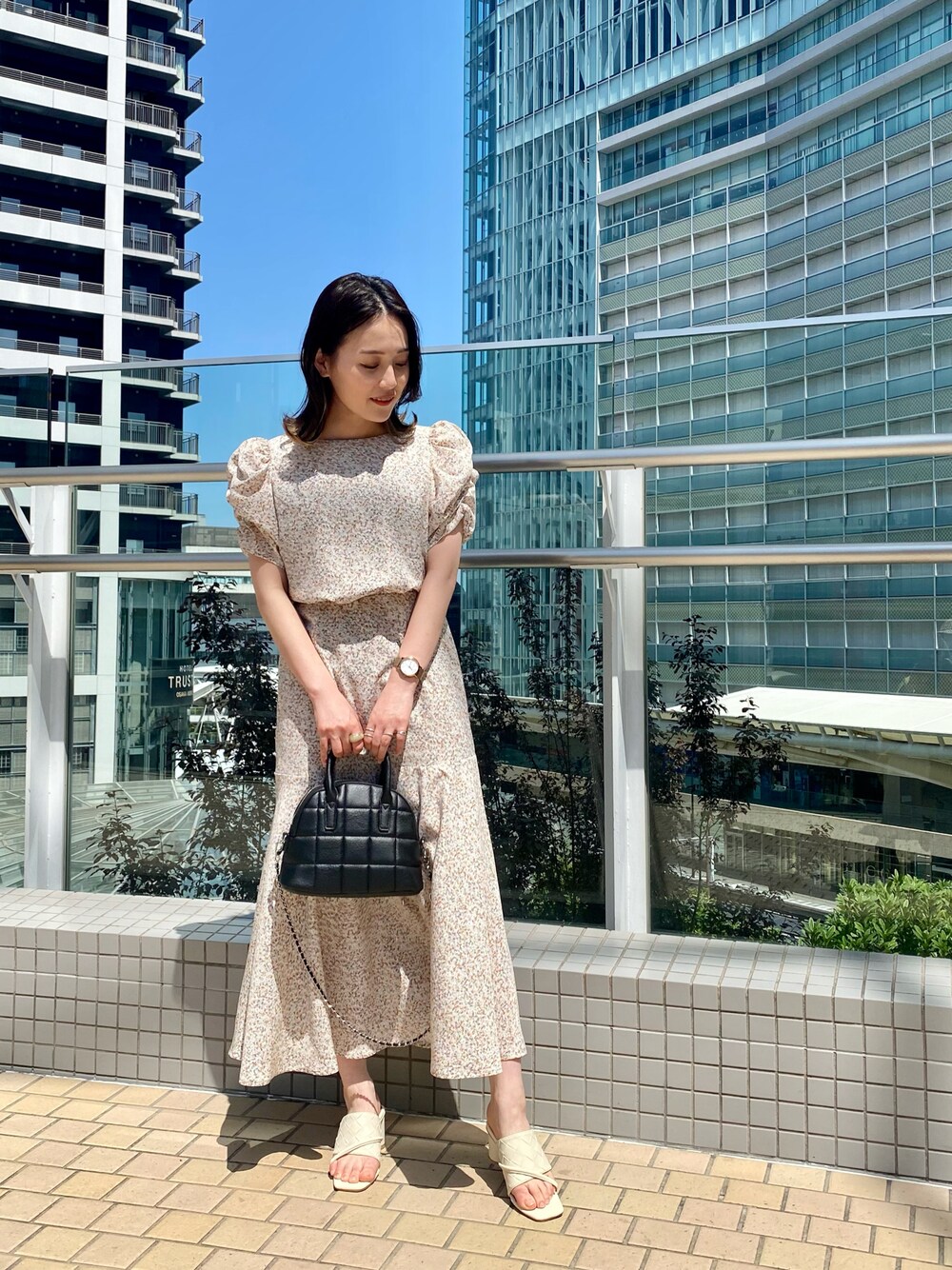 ホワイト系のサンダル、ブラック系のショルダーバッグ、ベージュ系のワンピースを着用したレディースの春コーディネートの1枚目の写真