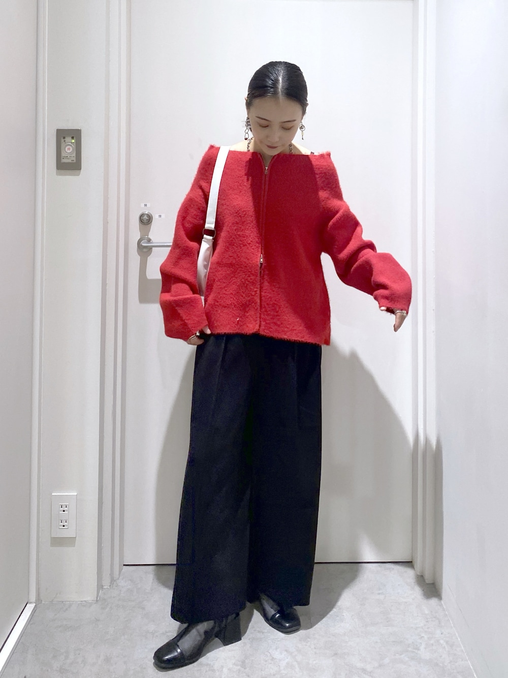 ブラック系のスラックス、レッド系のニット/セーターを着用したレディースの秋コーディネートの1枚目の写真