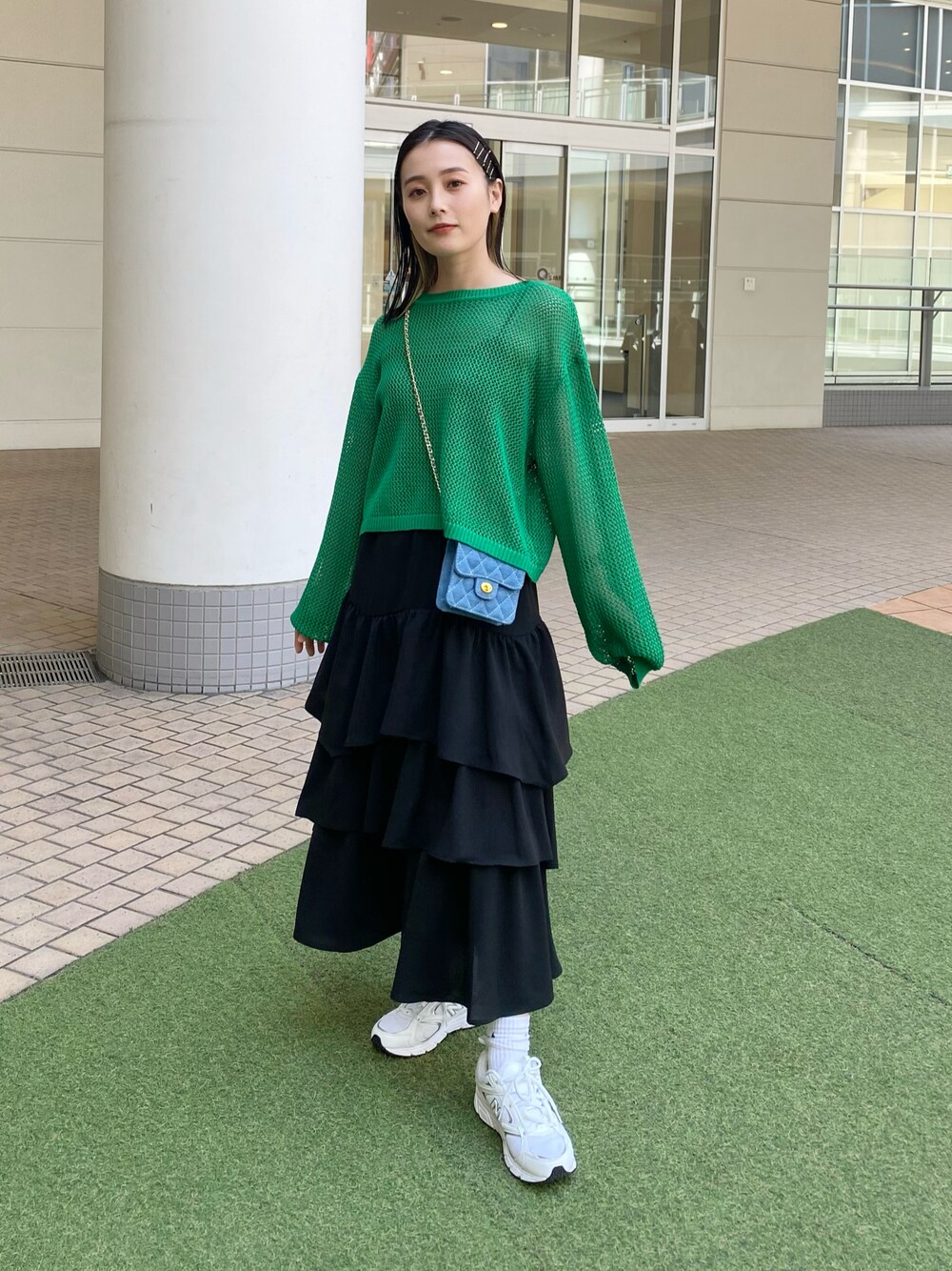 ブラック系のスカート、グリーン系のニット/セーター、ブルー系のバッグを着用したレディースの春コーディネートの1枚目の写真