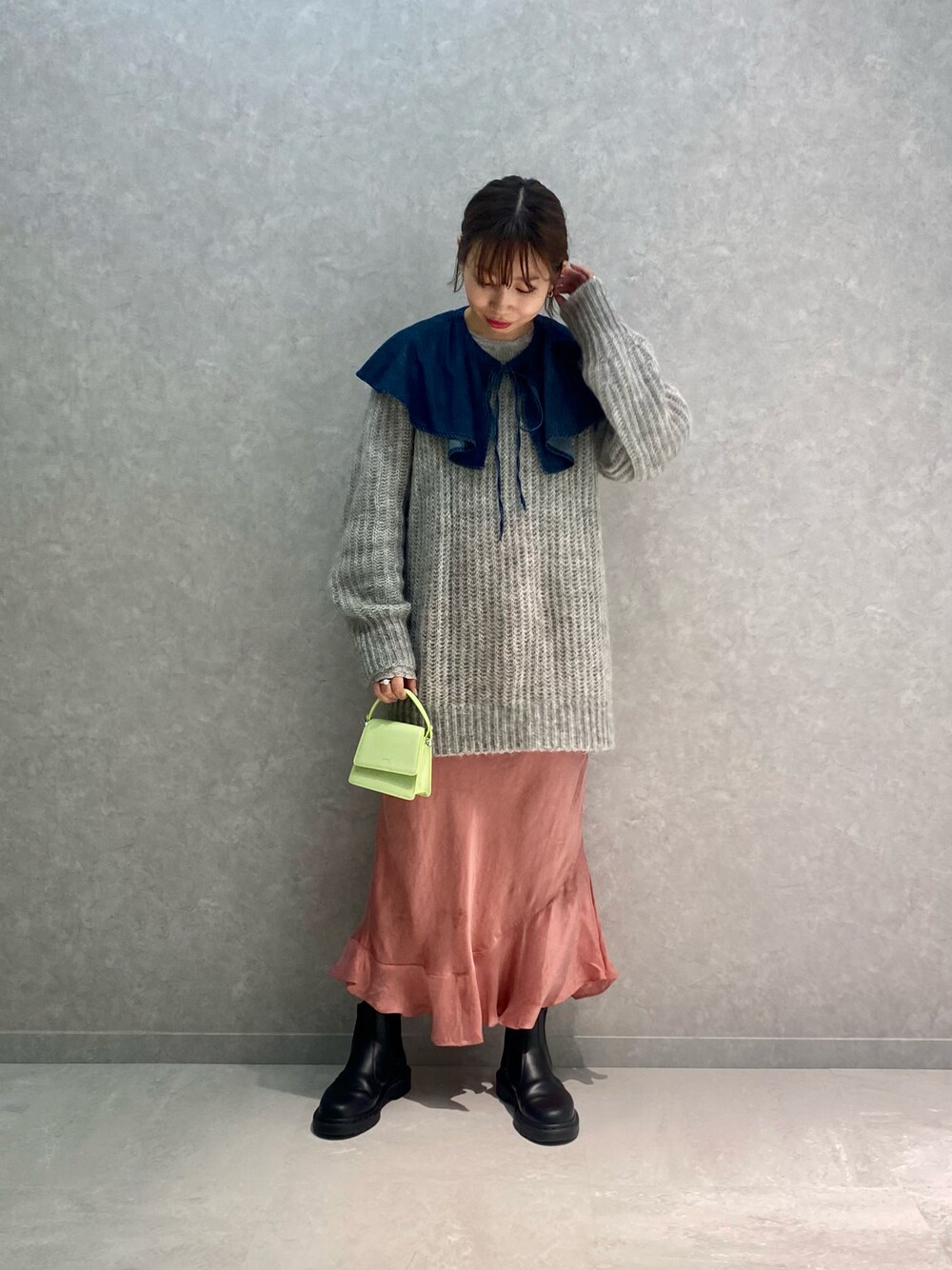 グレー系のニット/セーター、ブルー系のシャツ/ブラウス、グリーン系のバッグを着用したレディースの冬コーディネートの1枚目の写真