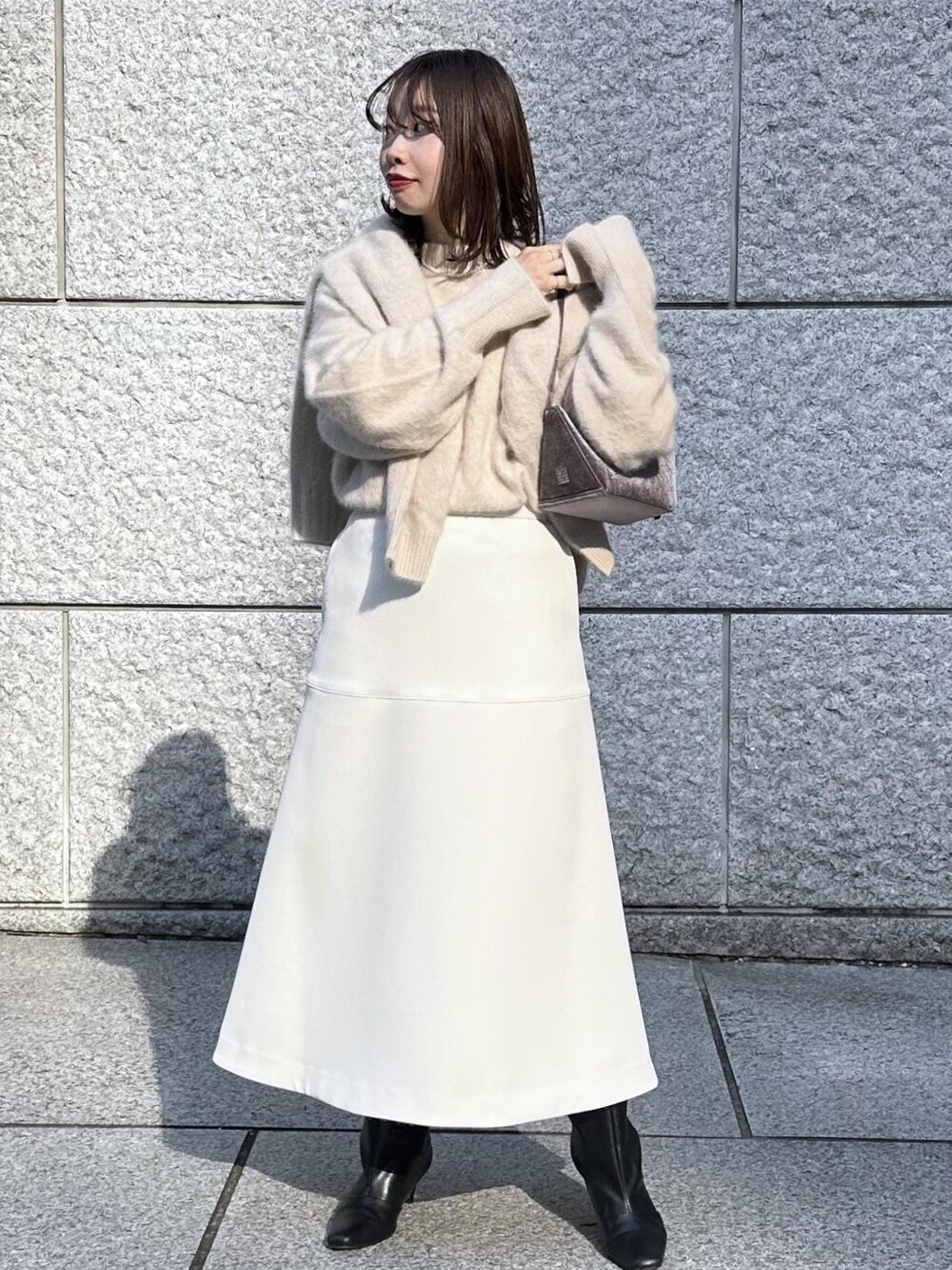 ホワイト系のスカート、ベージュ系のカーディガン/ボレロ、ベージュ系のニット/セーターを着用したレディースの秋コーディネートの1枚目の写真
