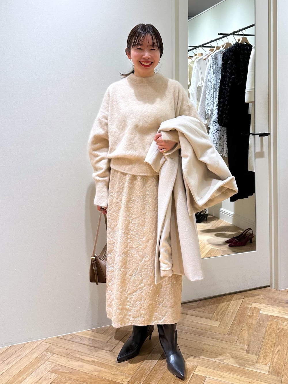 ブラック系のブーツ、ベージュ系のスカート、ベージュ系のニット/セーターを着用したレディースの冬コーディネートの1枚目の写真